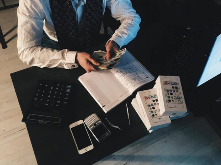 Businessman organizing finances with tech devices and cash on desk. bookkeeping