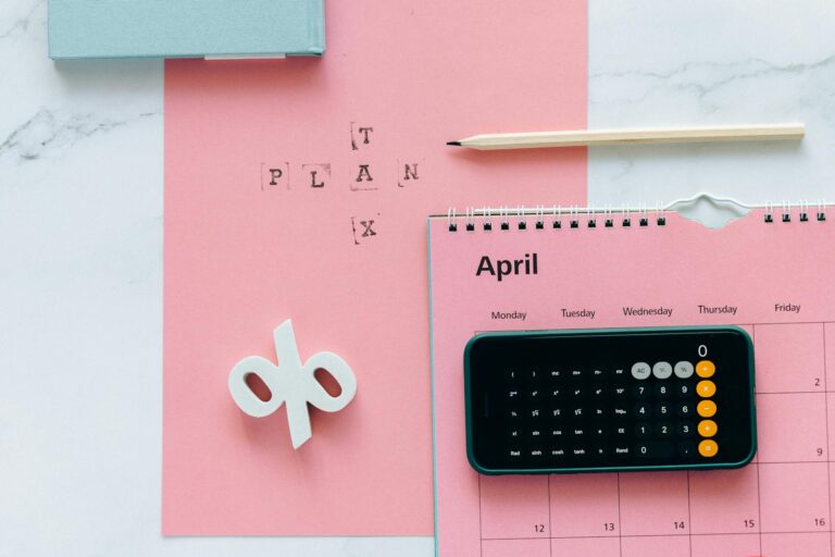 Flat lay of April calendar with calculator, pencil, and pink background for financial planning. tax planning services
