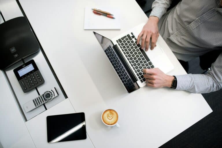person using laptop on white wooden table outsourced finance and accounting